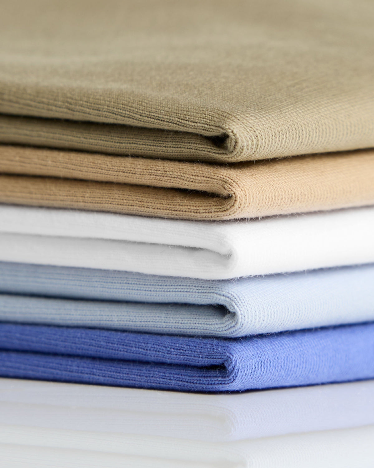 Stack of neatly folded classic heavyweight cotton t-shirts in earthy tones and blues perfect for workwear uniforms
