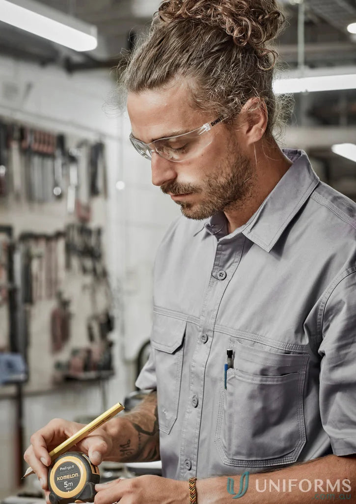 Man in safety glasses measuring with tape wearing Syzmik Mens Lightweight Tradie Short Sleeve Shirt zw120