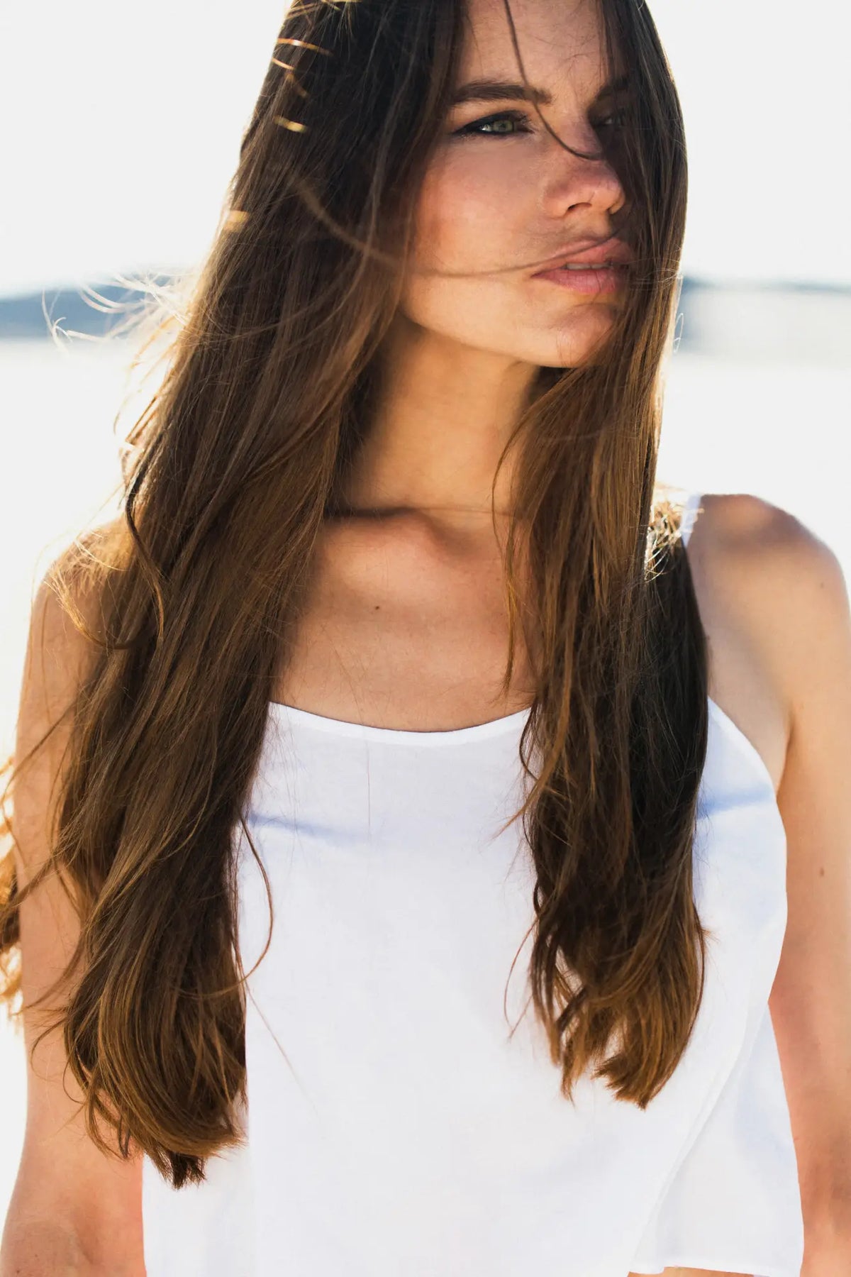 Young woman with long brown hair wearing a white AS Colour T shirt for workwear