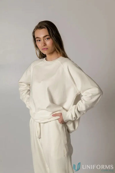 Woman wearing a matching cream Archie Crew Sweat sweatshirt and sweatpants for a comfy look