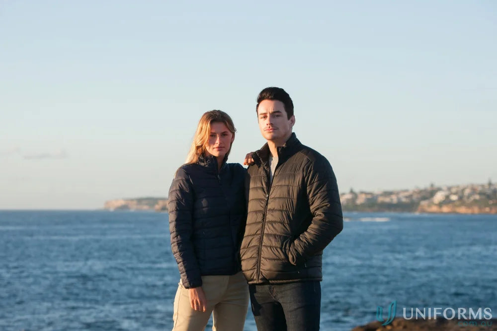 Two women wearing warm l7682 ladies puffer jackets by the sea, stay warm in style